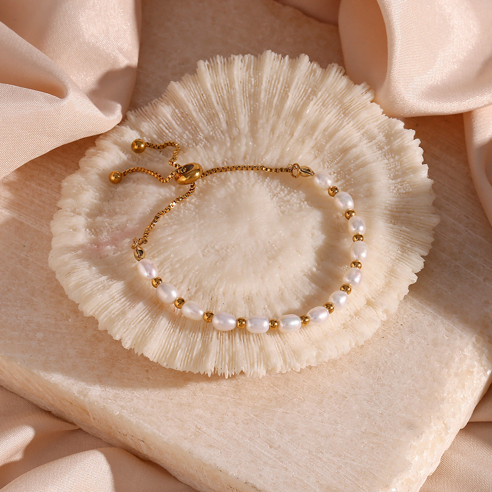 Pearl bracelet with gold accents on a decorative stone surface