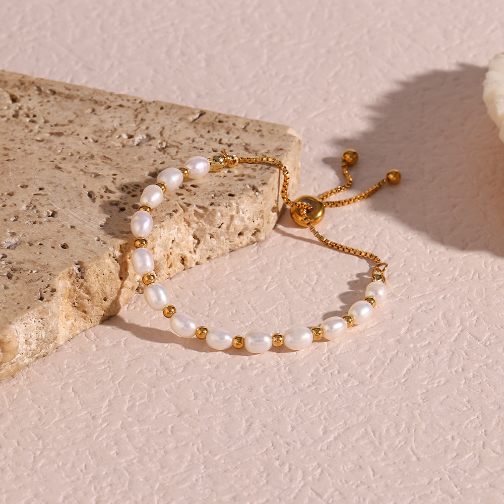 Pearl and gold bracelet on a textured stone surface