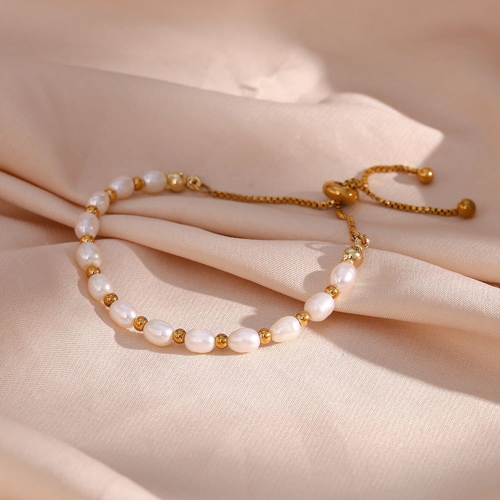 Pearl bracelet with gold accents on a soft beige fabric background