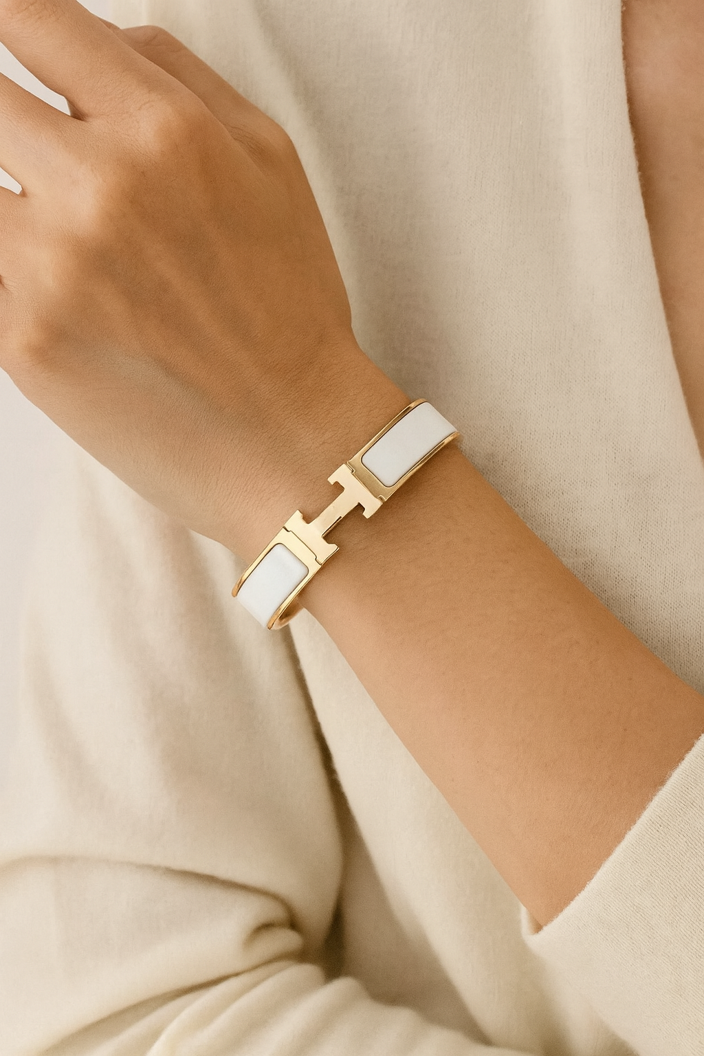 Gold and white bracelet on a wrist with a neutral background