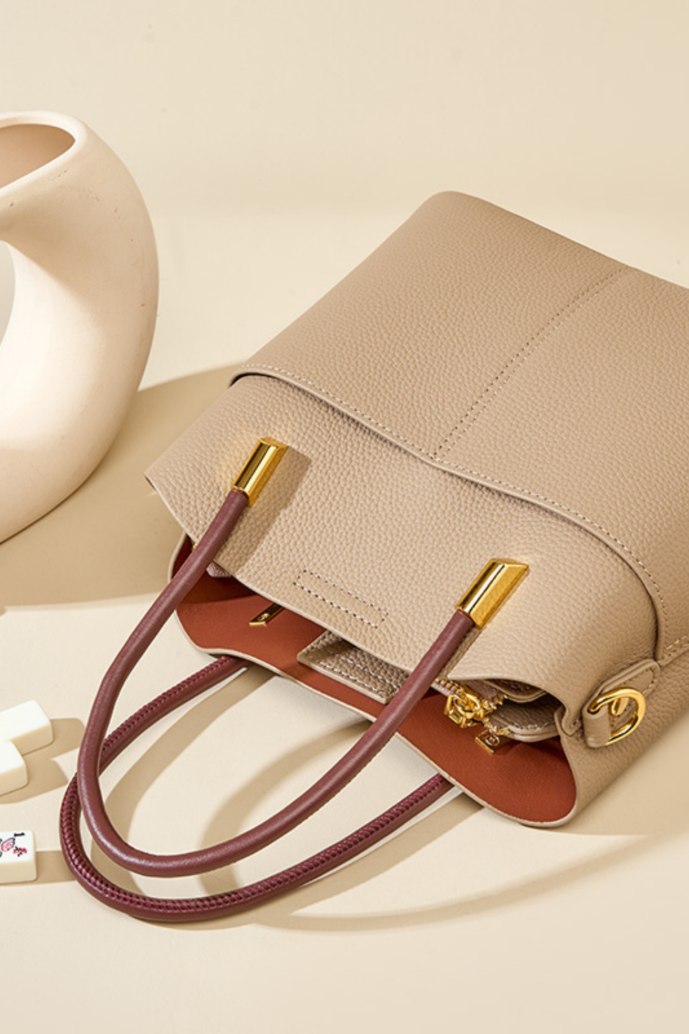 Beige handbag with brown handles on a beige background