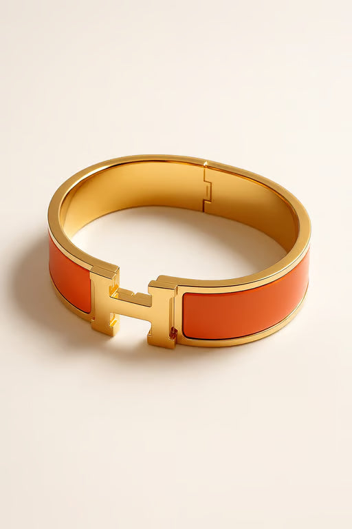 Gold bracelet with orange accents on a beige background