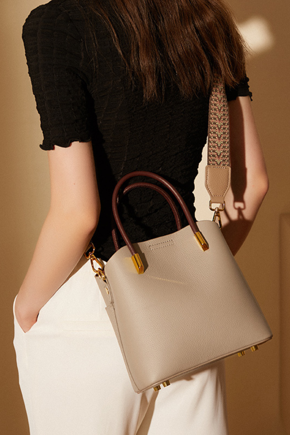 Person holding a beige handbag with a blurred background