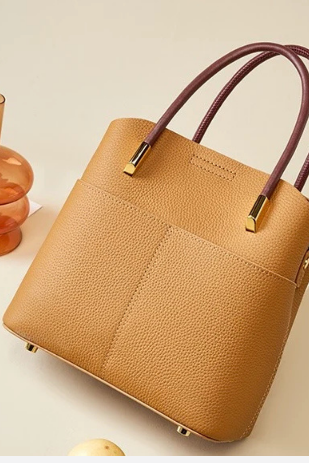 Brown handbag with gold accents on a light beige background
