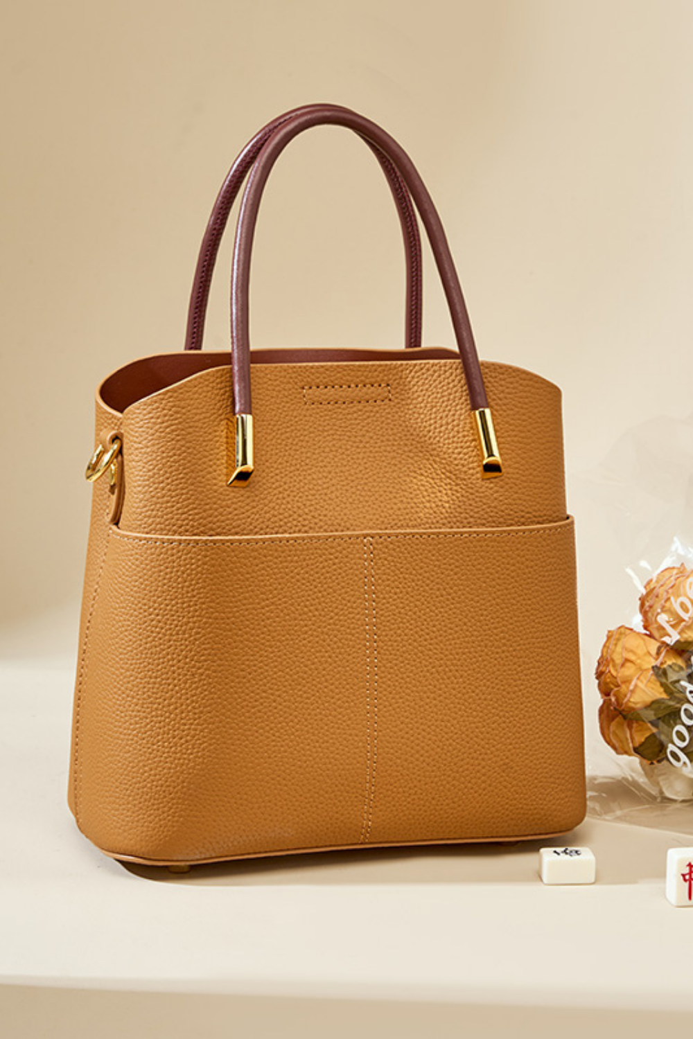 Brown handbag with gold accents on a beige background